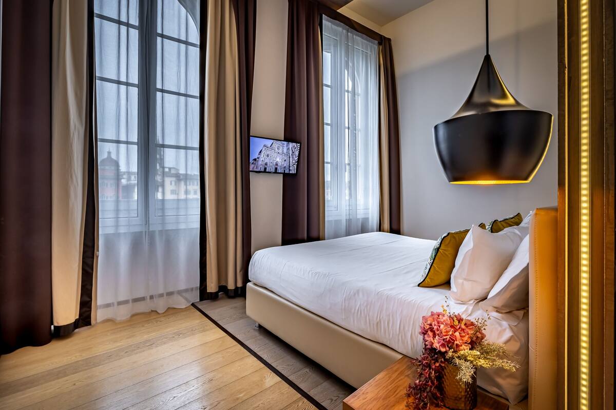 Camera d'albergo con un letto grande, una TV a parete e vista su un edificio.