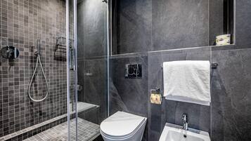 Un baño moderno con cabina de ducha de vidrio, inodoro blanco, lavamanos y toallero.