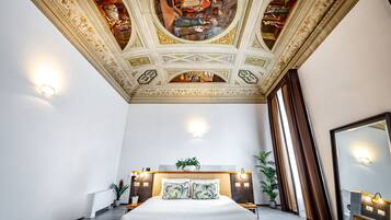 Un dormitorio espacioso con una cama grande, un techo con detalles artísticos y un baño moderno con un espejo amplio.