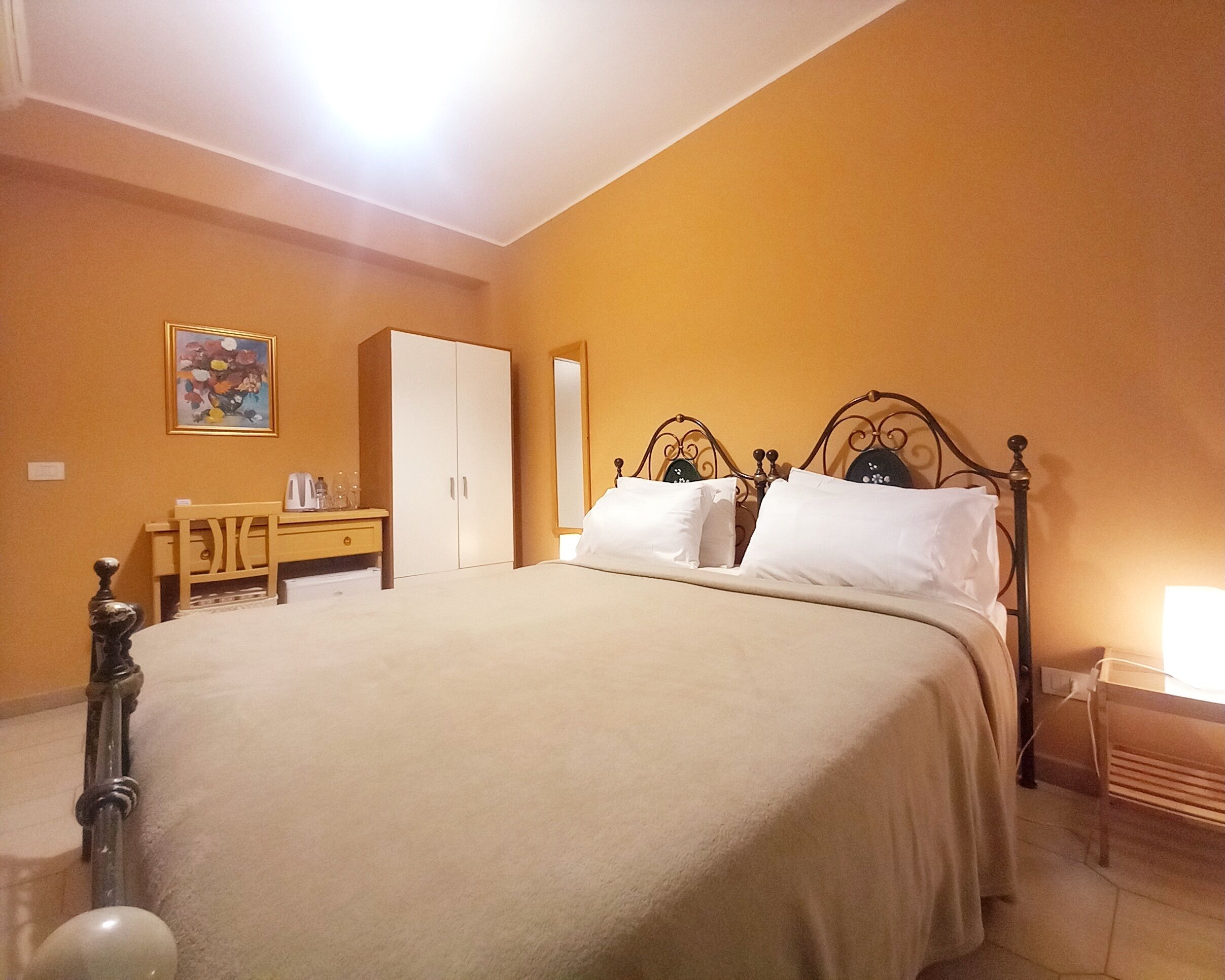 A bedroom with a bed, a wardrobe, a bedside table, and a mirror.