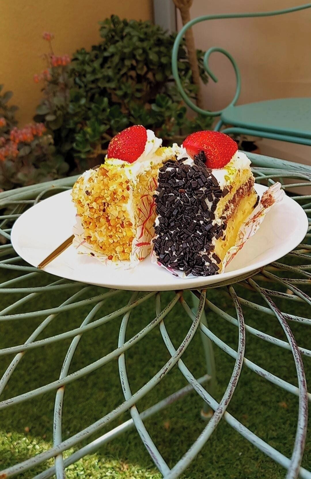 A slice of cake on a white plate on a metal table.