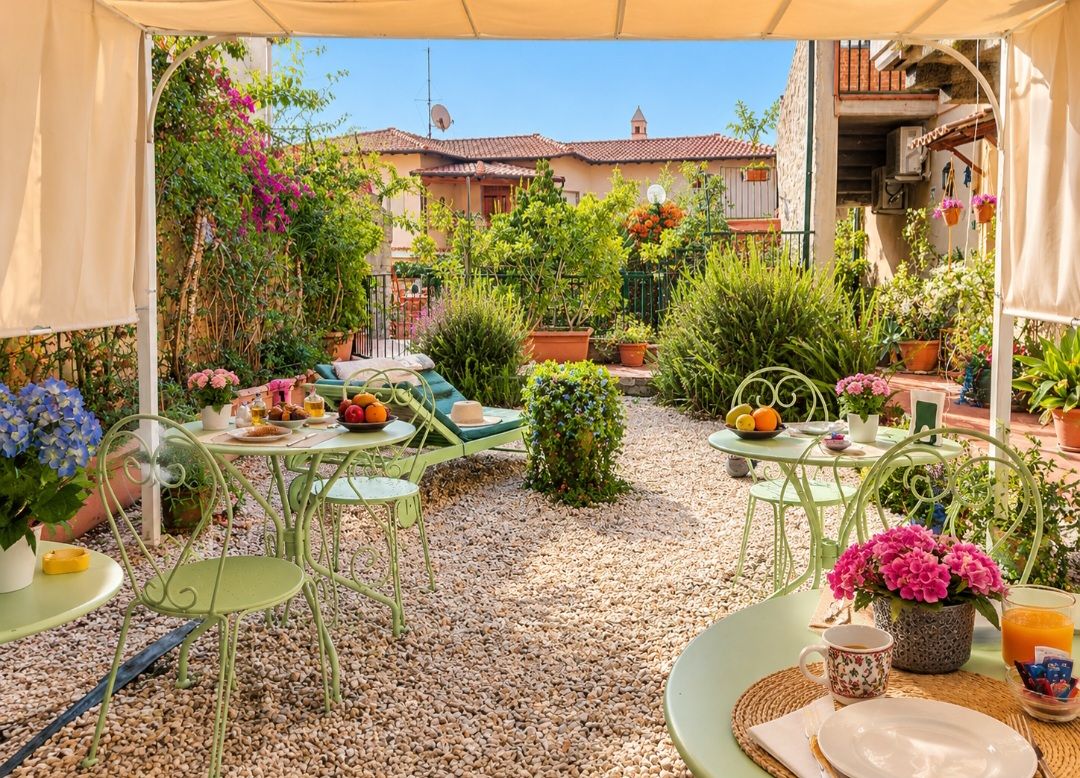 An outdoor patio with multiple tables and chairs, surrounded by potted plants and a gravel floor.