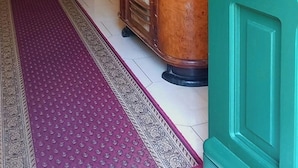 A hallway with a wooden cabinet, a vase with flowers, a mirror, and a blue sofa. - B&B Rosangela (Taormina)