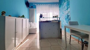 A compact room with a white sofa, a glass table, and a cabinet with storage. - B&B Rosangela (Taormina)
