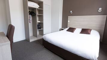 A hotel room with a bed, a wardrobe, a desk, and a chair.