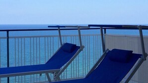 Ein Balkon mit zwei blauen Loungestühlen, der zum Meer hin ausgerichtet ist.