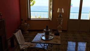 Ein Zimmer mit Meerblick, ein Tisch mit einer Flasche, ein Stuhl und eine Lampe.