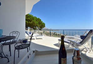Een balkon met een tafel, stoelen en een fles champagne.