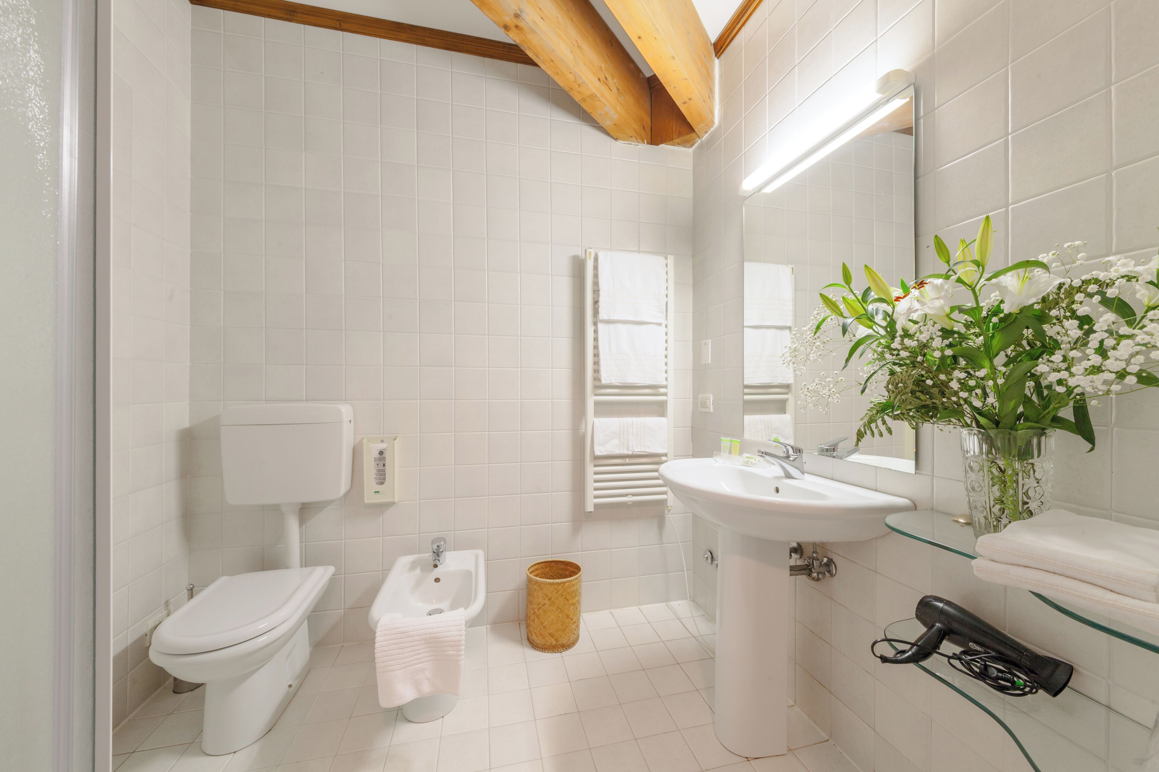 A bathroom with a toilet, bidet, sink, and a mirror.
