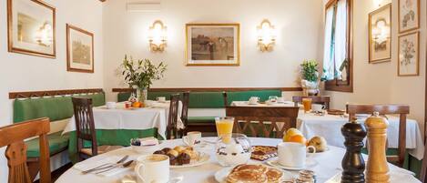 A breakfast setting with tables, chairs, and a variety of breakfast items.