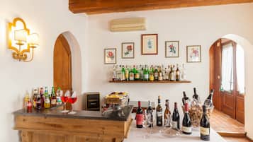 A bar area with a wooden counter, shelves with bottles, and framed floral artwork on the wall.