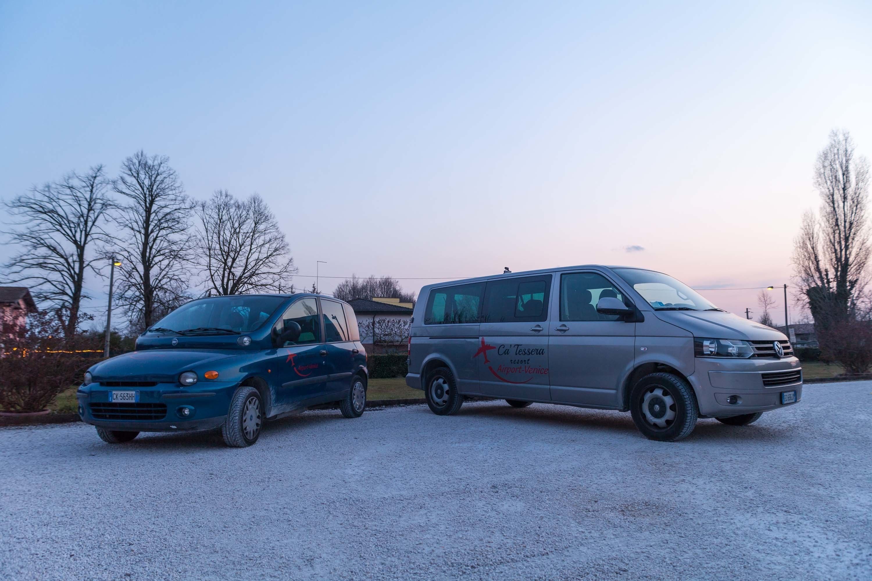 Two vehicles parked on a gravel surface with a clear sky in the background.