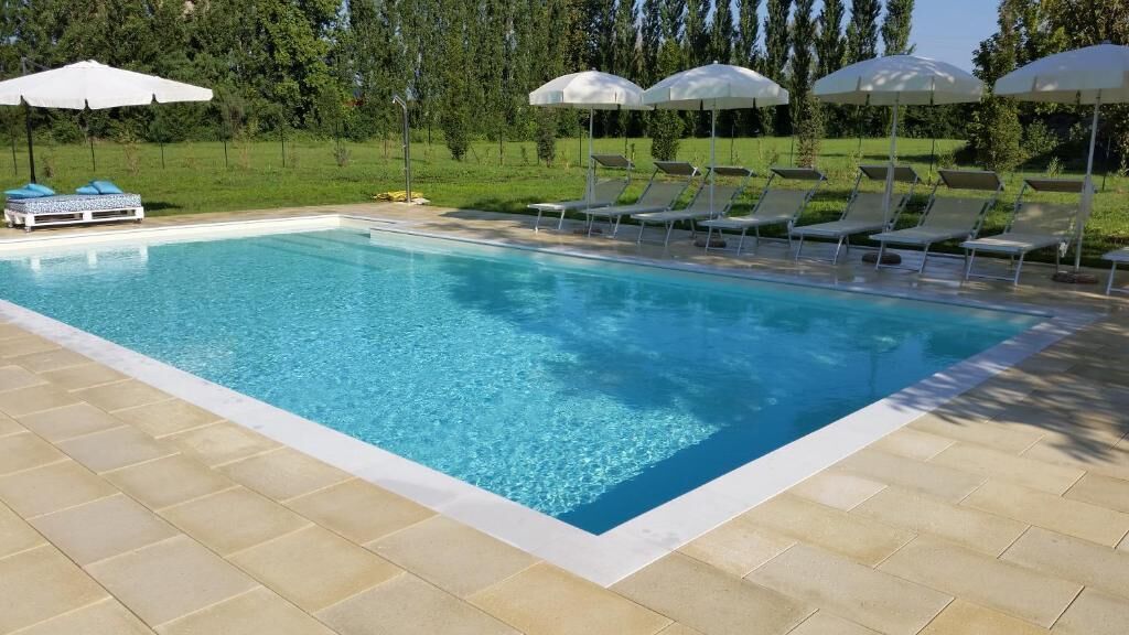 Een rechthoekig zwembad met helderblauw water, omringd door beige tegels.
