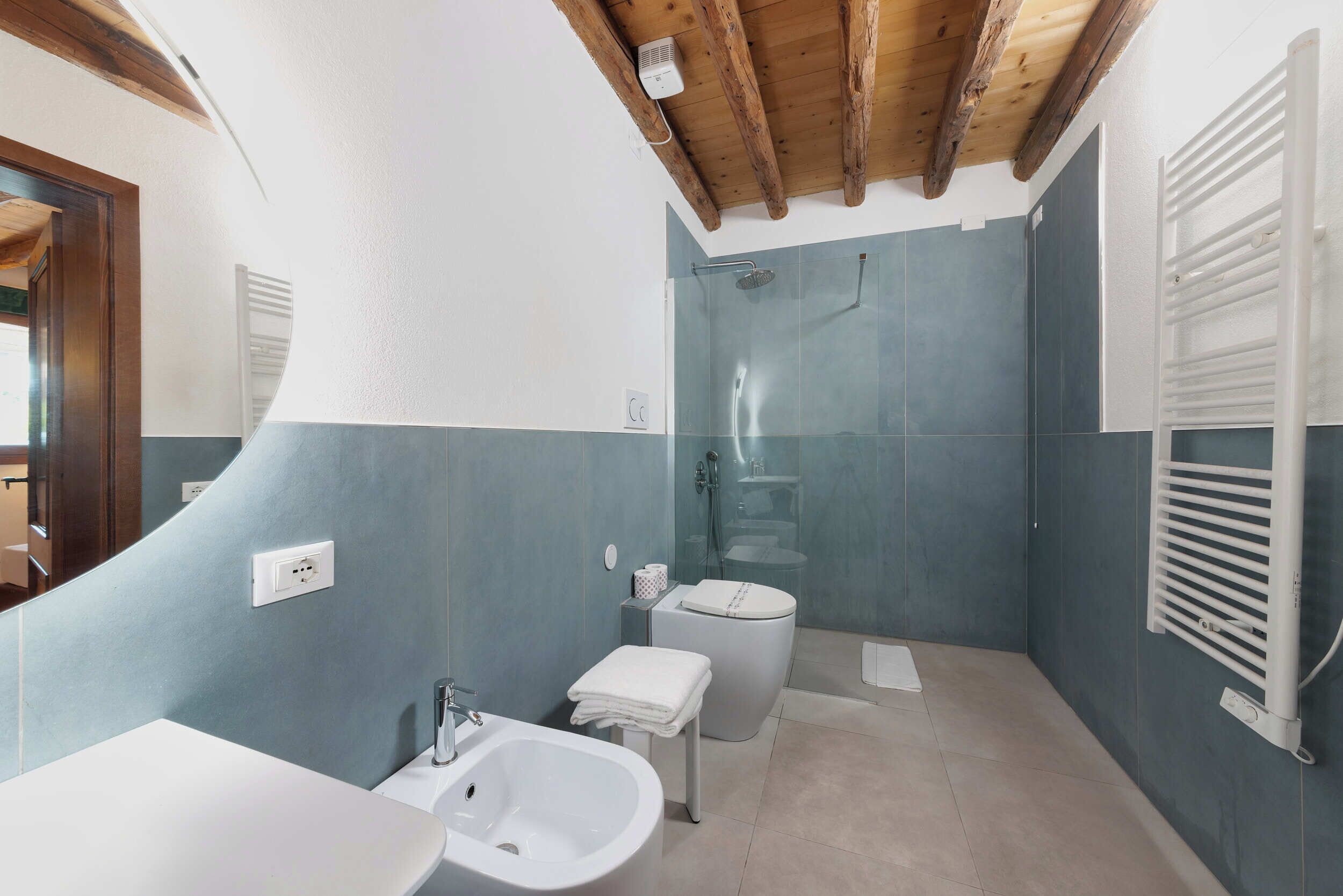 A bathroom with a shower, toilet, sink, and towel rack.