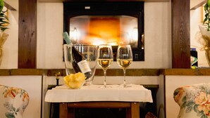 Una chimenea encendida, una botella de vino y dos copas sobre una mesa.