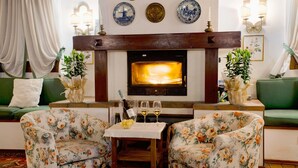 Una sala de estar acogedora con chimenea, sofás verdes, sillones estampados y placas decorativas en la pared.