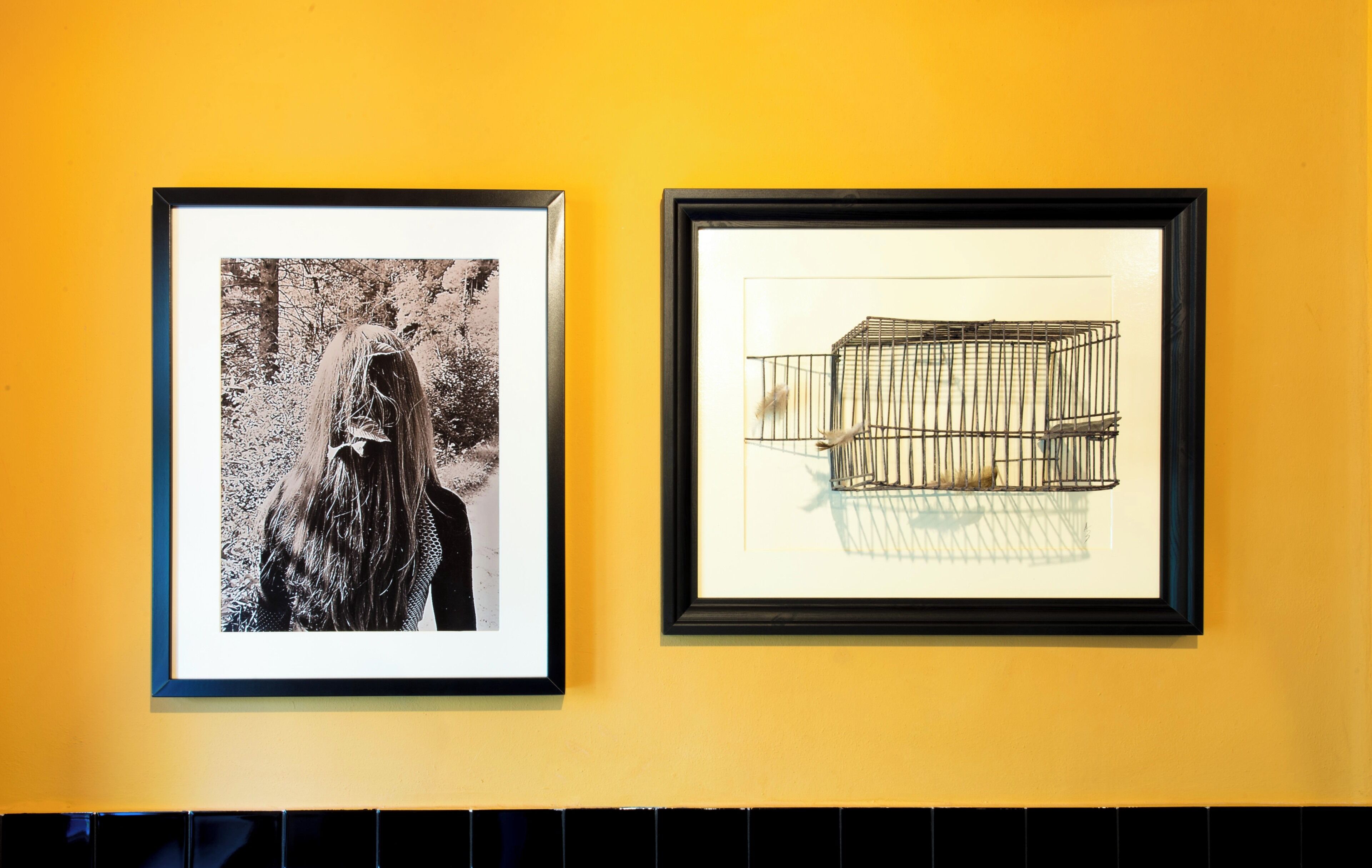 Two framed artworks on a yellow wall.