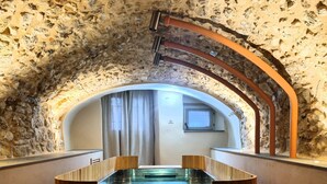 Une pièce aux murs de pierre, avec une baignoire en bois et une fenêtre.