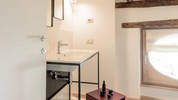 Un baño con techo de madera, un lavamanos blanco, un espejo y una ventana con vistas.