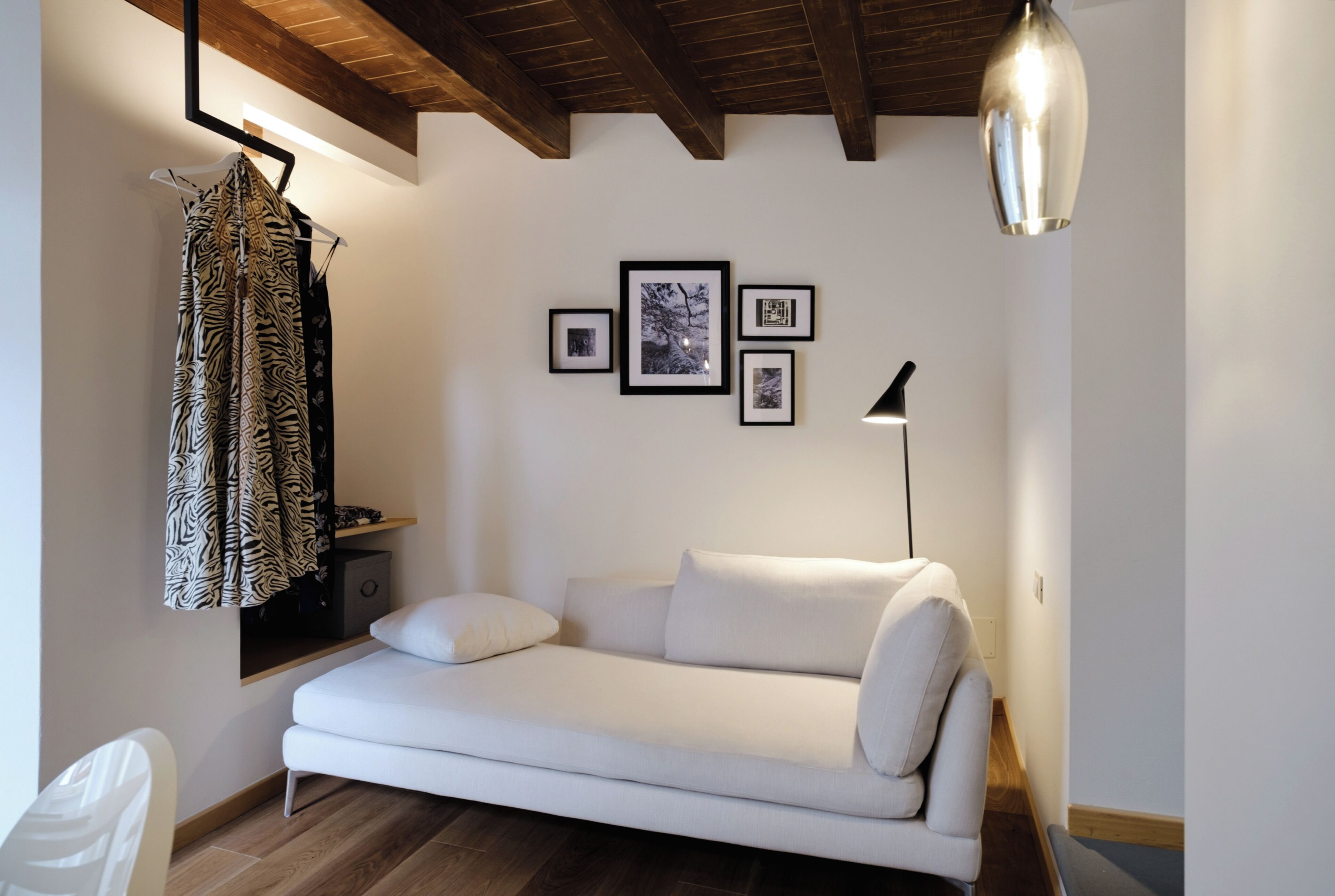 Un salon moderne avec un canapé blanc, un luminaire suspendu et des tableaux encadrés accrochés au mur.