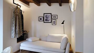 Un salon moderne avec un canapé blanc, un luminaire suspendu et des tableaux encadrés accrochés au mur.