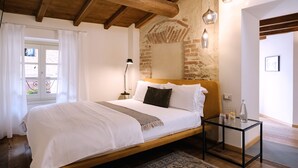 Une chambre à coucher avec un lit en bois, une table de chevet, une lampe et une table en verre sur laquelle se trouve une bouteille.