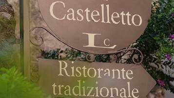 A sign for 'Locanda al Castello Ristorante tradizionale' with a rustic metal frame and decorative swirls.