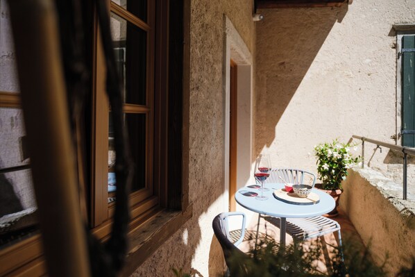 A small outdoor seating area with a table and chairs, a window with a view, and a potted plant. - Locanda Al Castelletto (Tremosine)