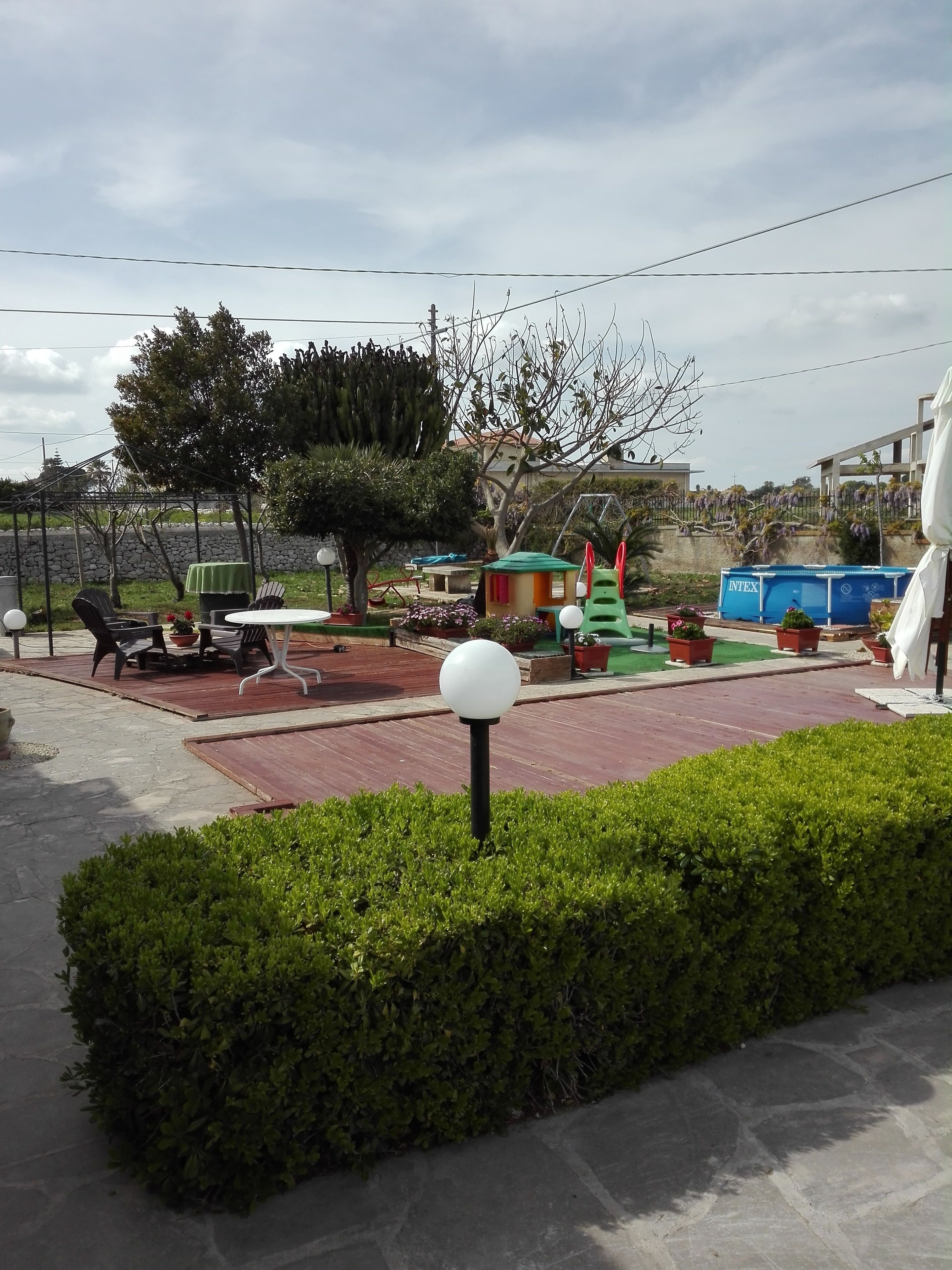 Un parque con un área de juegos, zona de descanso y un pequeño edificio con techo verde.