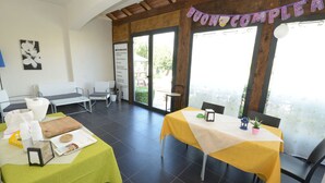 Ein Essbereich mit gedeckten Tischen, einer Speisekarte und einem 'Buon Compleanno'-Banner.