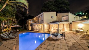 Une maison à deux étages avec une piscine, du mobilier d’extérieur et un espace patio.