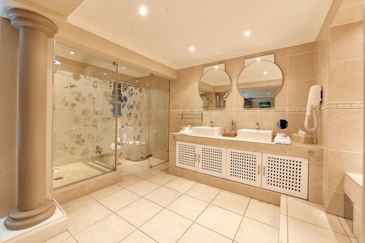A modern bathroom with a glass-enclosed shower, a double sink vanity, and a large mirror above the sink.