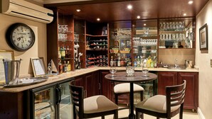 Un espace bar agrémenté d’une horloge, d’étagères remplies de verres et d’un meuble à vin.
