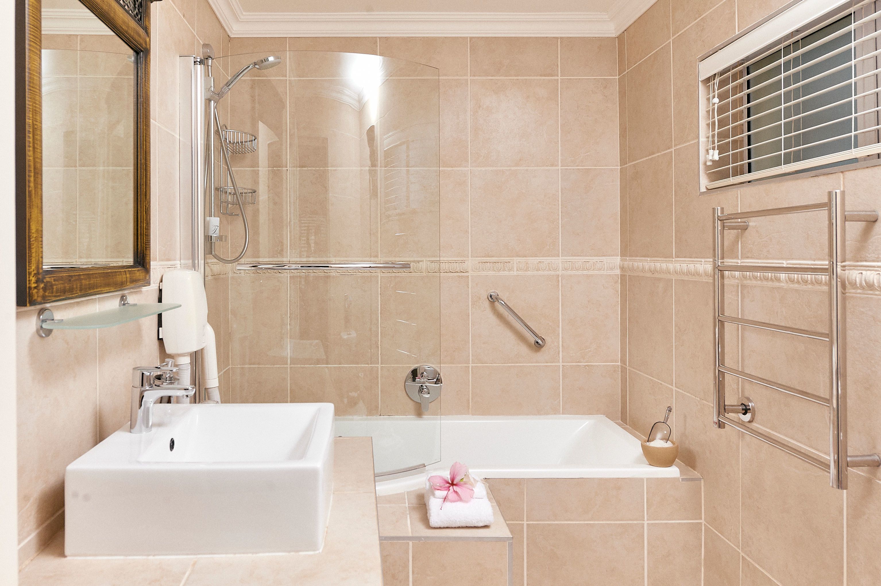 Un baño moderno con bañera, ducha, lavabo y espejo.