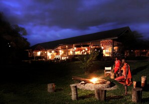 A lodge with a large open dining area and a fire pit in the foreground.
