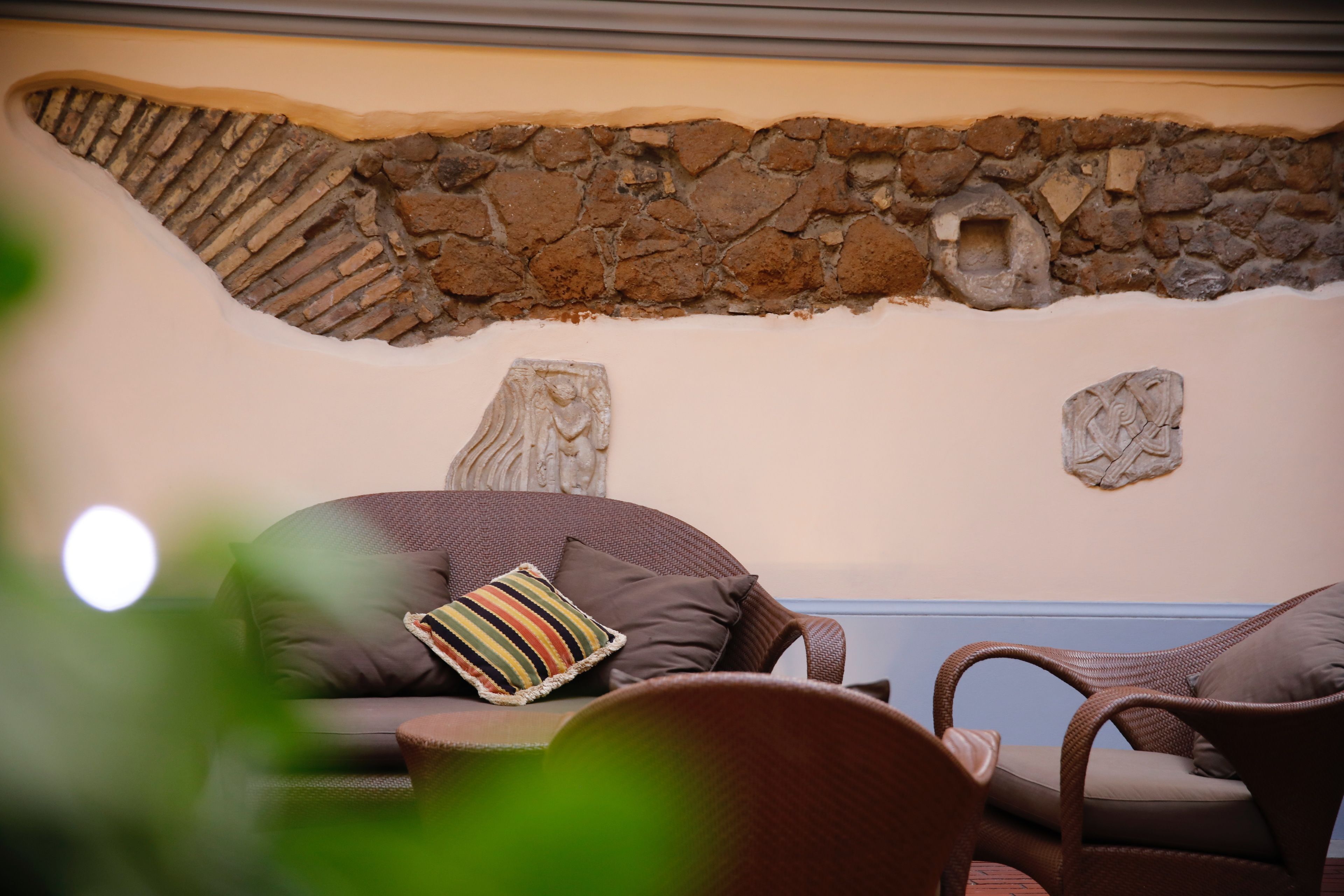 Ein gemütlicher Sitzbereich mit Steinwand, einem gewebten Sofa und einem Korbstuhl.