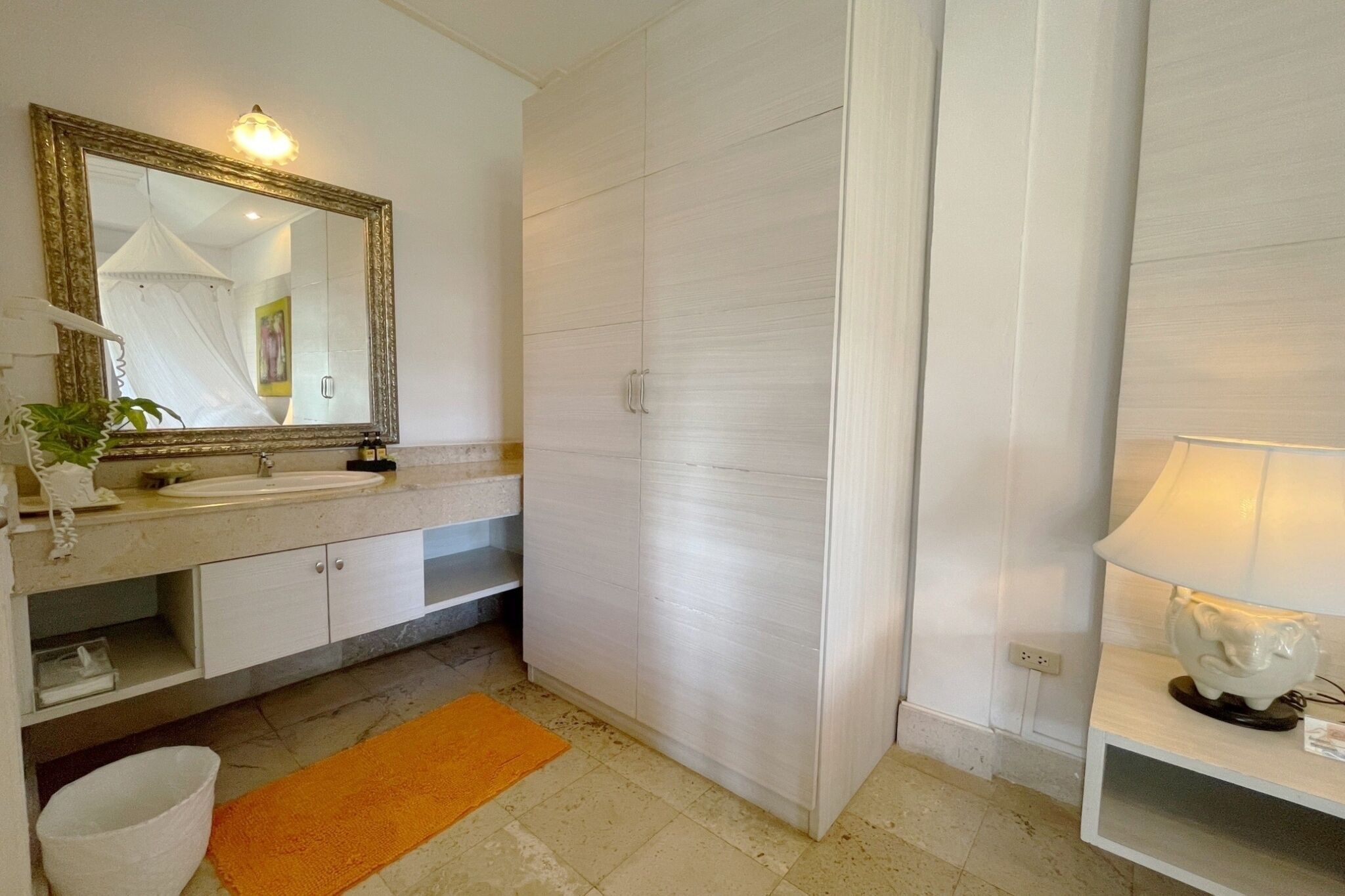 Un baño con lavabo, espejo, armario y toallero.
