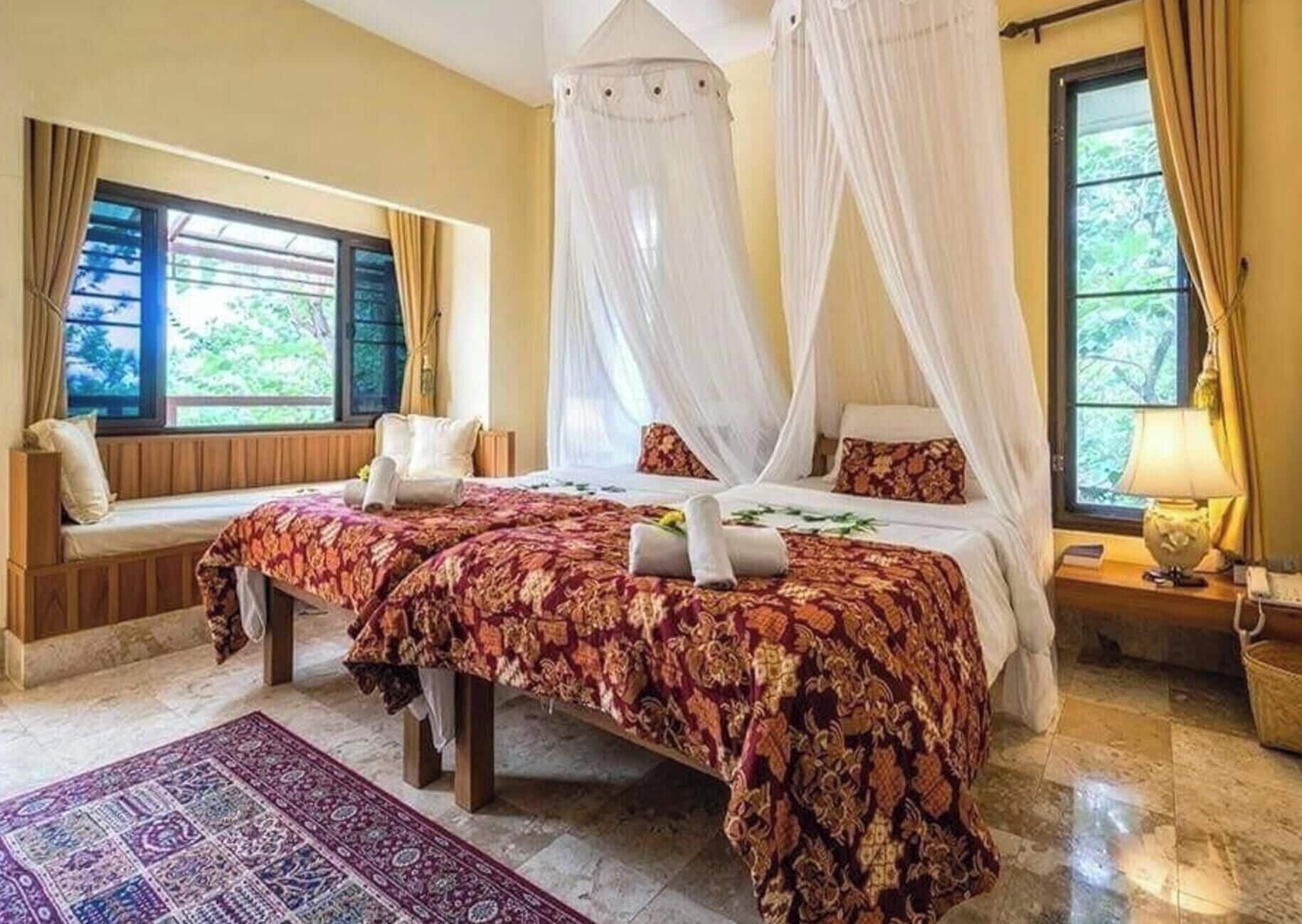Ein Schlafzimmer mit einem Himmelbett, einer Bank und Blick auf Grünfläche.