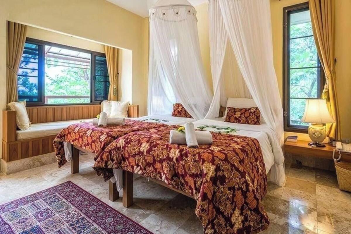 Une chambre à coucher avec un lit, un banc, une fenêtre et une table de chevet.