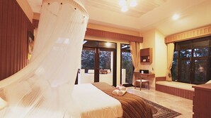 Une chambre à coucher comprenant un lit, un bureau, une chaise, une grande fenêtre et une vue sur l’extérieur.