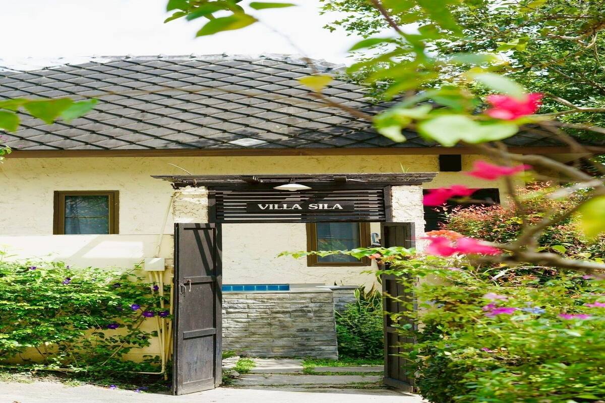 A villa named 'Villa Sila' with a tiled roof, a stone wall, and a wooden gate.
