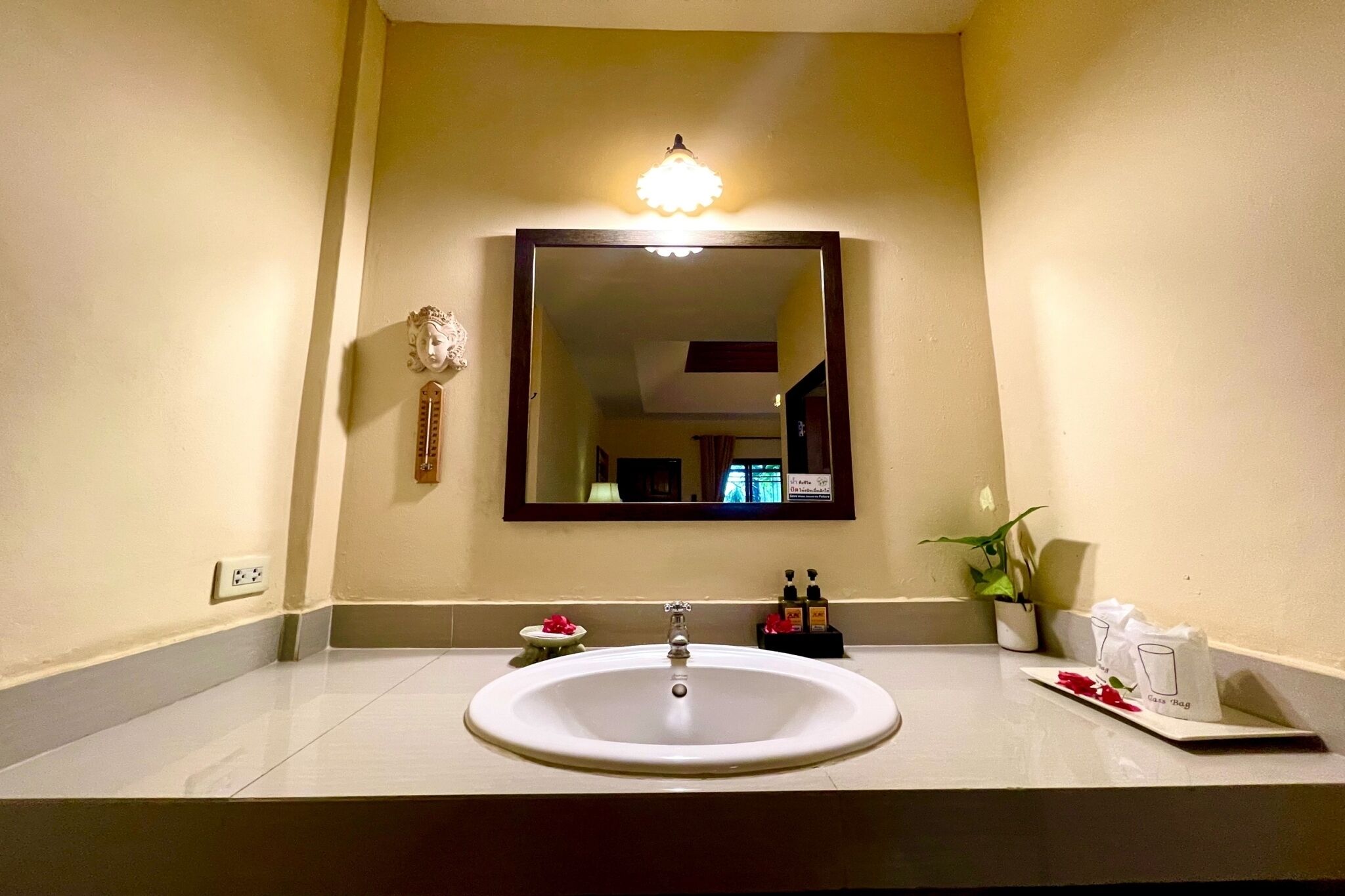 Une salle de bain avec un lavabo, un miroir et un luminaire placé au-dessus du miroir.