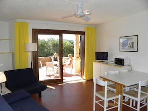 Una habitación con sofá, mesa de comedor, sillas, televisor y ventilador de techo.