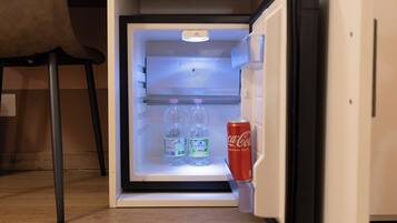 Un refrigerador abierto con dos botellas de agua y una lata de Coca-Cola.
