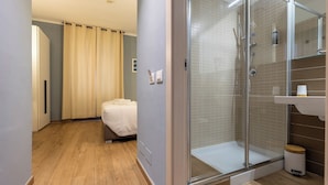 A hotel room with a shower, a bed, and a bathroom with a sink and mirror. - La Loggia de' Banchi (La Spezia)