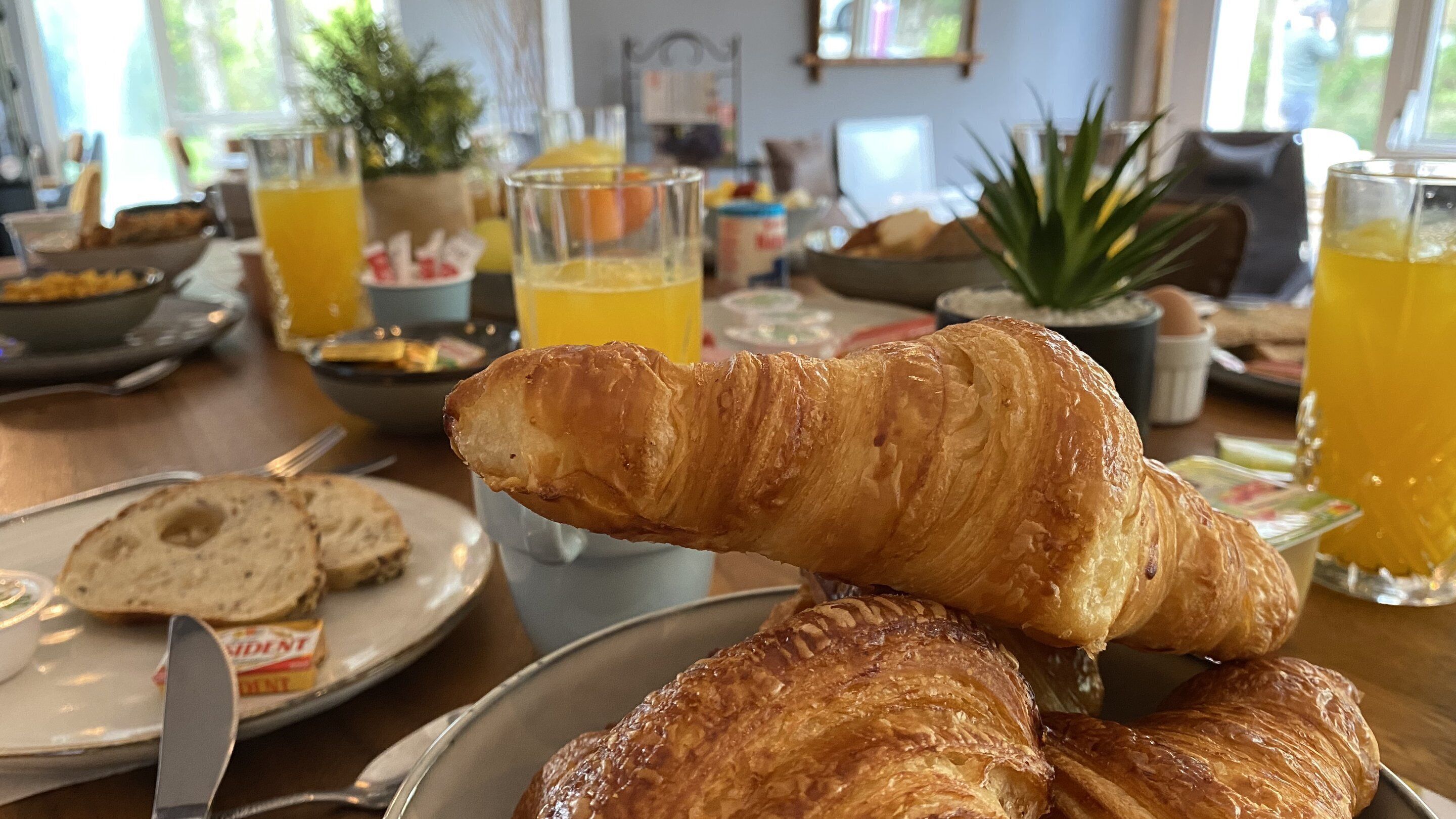 Een ontbijtsetting met croissants, sinaasappelsap en een kom ontbijtgranen.