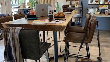 Un caffè moderno e luminoso con un tavolo in legno, poltrone in pelle e un laptop sul tavolo.