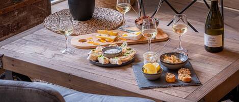 Una mesa de madera dispuesta con varios quesos, embutidos y copas de vino, evocando una experiencia gastronómica relajada.