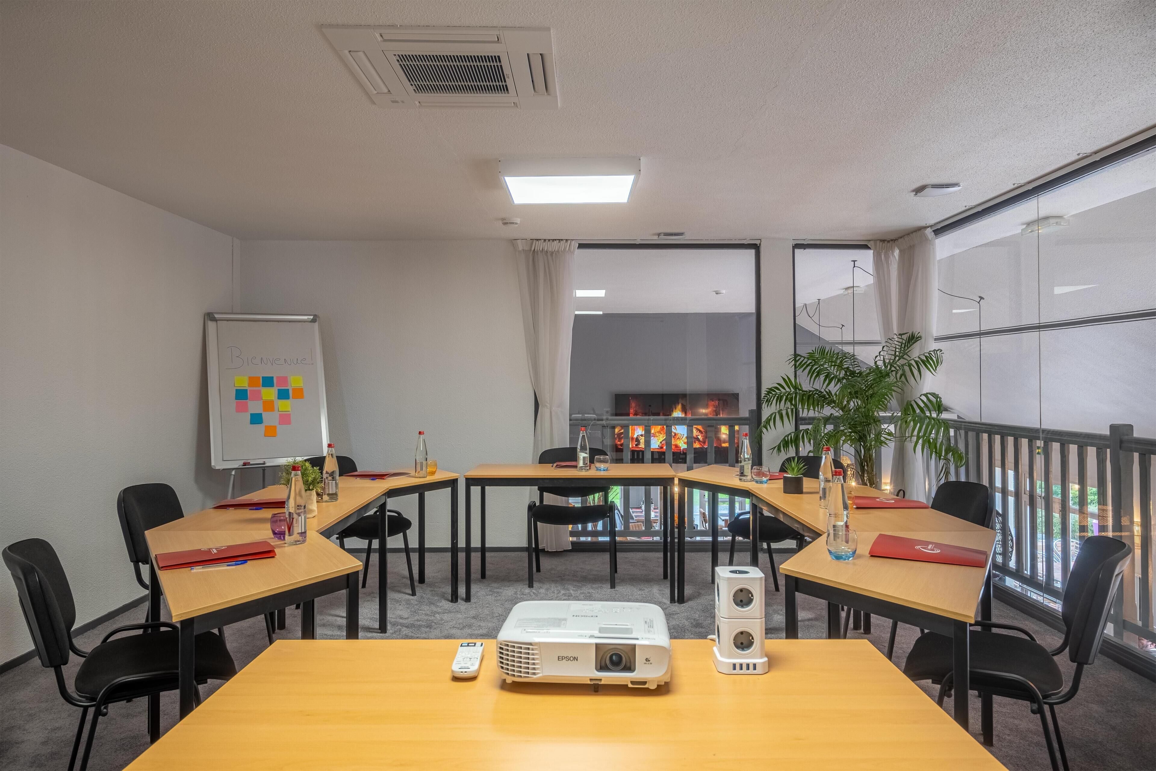 A conference room with a whiteboard, projector, and tables with chairs.