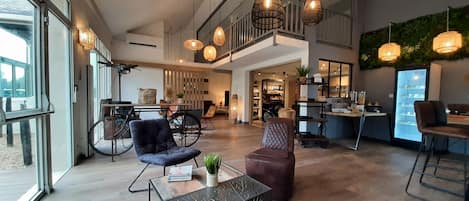 A spacious hotel lobby with a high ceiling, large windows, and a mezzanine level.